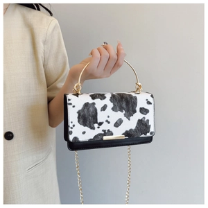 Détail du sac bandoulière à motif vache avec poignée dorée et chaîne sur modèle