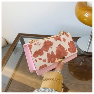 Détail d'un sac en cuir rose avec rabat imprimé animal et bandoulière chaîne dorée moderne