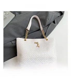Detail of woven leather tote bag featuring golden deer pendant and chunky chain strap