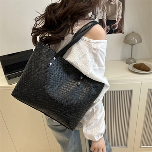 Minimalist black woven leather tote bag with slender straps for casual office use