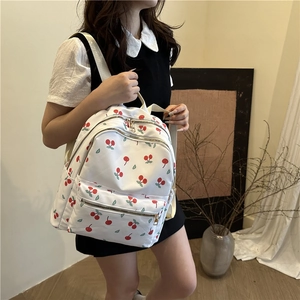 White nylon backpack with cherry pattern featuring gold zippers and adjustable straps