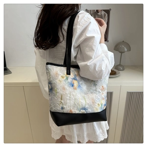 Detailed texture of floral chiffon fabric and black leather base on a large tote bag