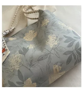 Detailed view of canvas tote bag with retro floral print and decorative woven silk handle