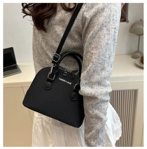 Detail view of black shell bag showing woven texture and adjustable shoulder strap