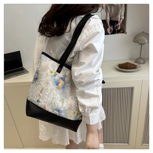 Detail of floral embroidered tote bag with black straps in a minimalist lifestyle setting