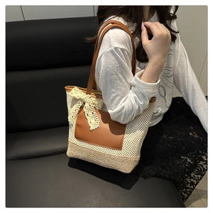 Detailed view of hand-woven straw tote with brown leather handles and lace bow detail