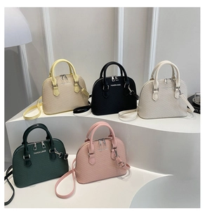 Five assorted colors of textured shell bags displayed on a white minimalist podium