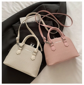 Detail of woven texture on beige and pink shell-shaped handbags with fashion slogan