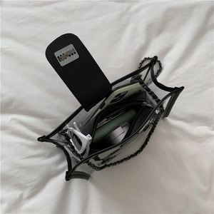 Clear PVC crossbody bag with black trim and chain strap holding daily essentials