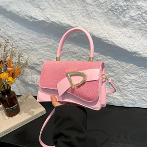 Detail of pink crossbody bag with gold D-ring buckle and elegant bow decoration