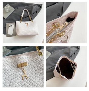 Detail view of woven white tote bag with golden deer charm and spacious interior