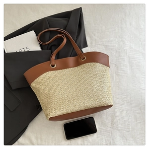 Detailed top view of large woven straw tote bag with brown leather handles and base