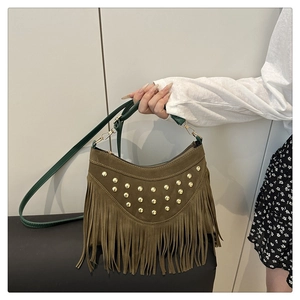 Detailed close-up of dark green suede fringe and golden metal rivet studs on a handbag