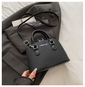 Close-up of black shell handbag showing textured material and metallic zip hardware