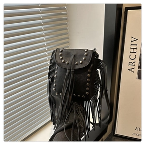 Close-up of black leather crossbody bag featuring vintage fringe and silver rivet details