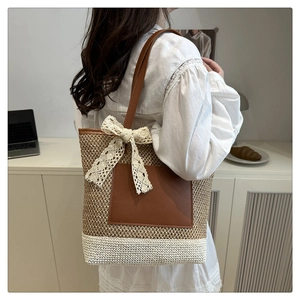 Detail of woven tote bag featuring brown leather pocket and delicate lace bow