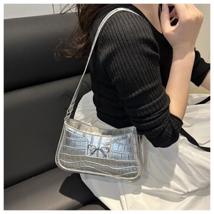 Close-up of silver crocodile embossed shoulder bag with metallic bow detail