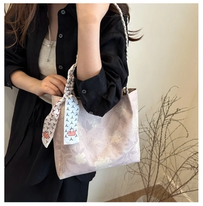 Detail of floral tote bag with lavender print and decorative handle scarf detail