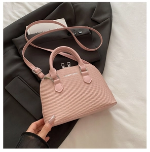 Detail of pink shell-shaped crossbody bag with woven texture and top handles