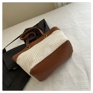 Close-up of the woven straw texture and premium brown leather handle on a tote bag