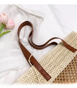 Detalle de bolso de paja tejido a mano con rayas bicolor y correas de cuero marrón