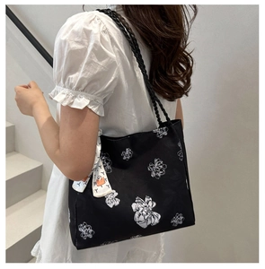 Detail of black canvas tote bag with white floral pattern and decorative silk scarf