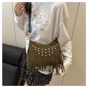 Detail van bruine suède crossbody tas met gouden studs en lange franjes eraan