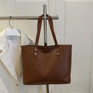 Detailed view of dark brown woven tote bag featuring silver rivets and grid texture