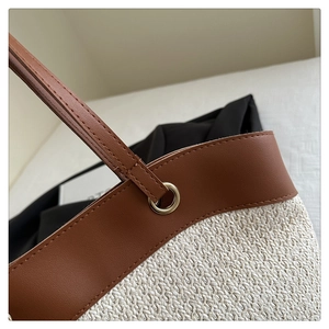 Detail of the woven straw texture and premium brown leather trim with metallic eyelets