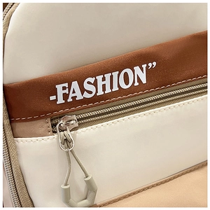 Detail of color-block backpack showing zip pocket, stitching, and FASHION lettering