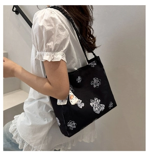 Detail of floral print tote bag featuring woven straps and decorative side scarf