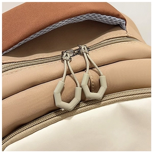 Detail of color-block backpack showing dual zippers and hexagonal pullers close-up