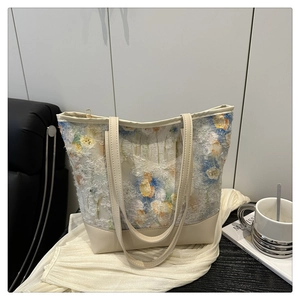 Detail view of the floral embroidery texture and beige leather handles on the tote bag