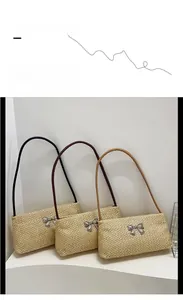 Détail du sac à bandoulière en paille tressée avec nœud argenté et trois options de couleurs