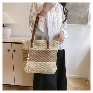 Detail of woven straw tote bag featuring contrast colors and decorative wood bead tassels