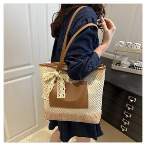 Close-up of woven straw tote bag with brown faux leather pocket and beige lace bow detail