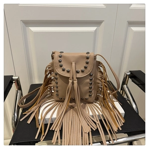Detailed view of bohemian tan leather crossbody bag with vintage rivets and long fringe tassels