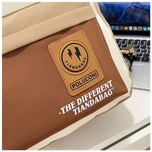 Detail of contrast color stitching and leather logo patch on canvas travel backpack