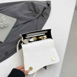 Sleek white asymmetrical flap crossbody bag showing spacious interior with daily items