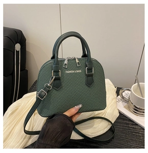 Detailed view of the dark green woven texture shell bag with silver metal hardware logo