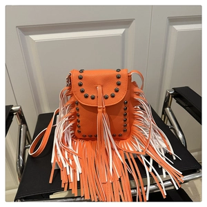 Detail of orange faux leather crossbody bag with long fringes and metal rivets