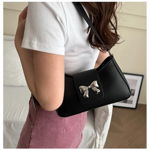 Detail view of a black matte leather underarm bag featuring a silver metal bow buckle