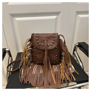 Detail of brown litchi pattern leather crossbody bag with vintage tassels and metal rivets