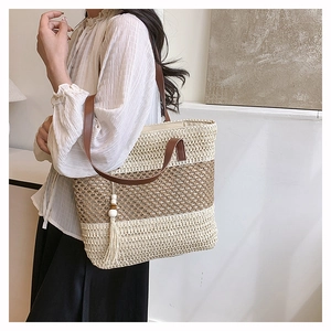 Detail of a large woven tote bag with tricolor patchwork, leather straps and tassel decor