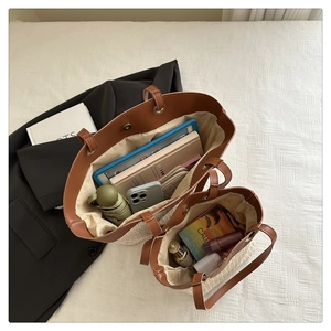 Detail of a beige woven tote set with leather handles showing large interior capacity