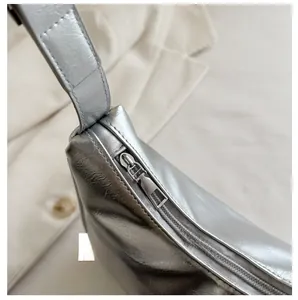 Detail shot of smooth metal zipper and silver metallic leather texture on the hobo bag