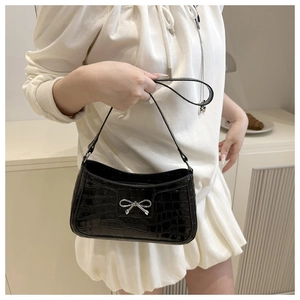 Detail of black crocodile texture shoulder bag with silver bow ornament and moon shape