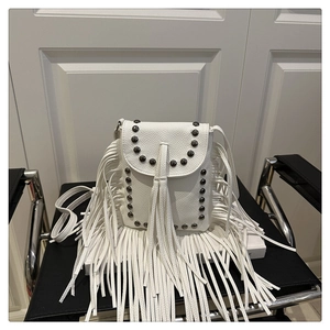 Close-up of white lychee leather crossbody bag with metal studs and long fringe tassels
