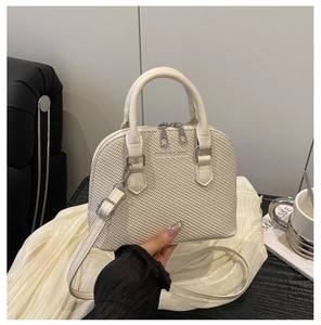 Detail showing cream woven texture and silver hardware of the retro shell handbag