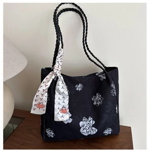 Close-up of black floral canvas tote bag with woven rope handles and a silk scarf detail